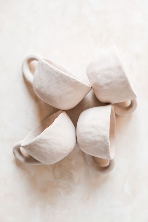 Four handmade white ceramic cups viewed from above
